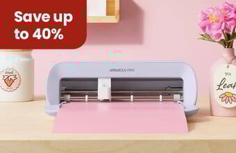 A shelf with cricut machine cutting some vinyl, with a jar and a vase with a tag with cut-out designs on them. A save up to 40%' badge. Clicking leads to cricut products